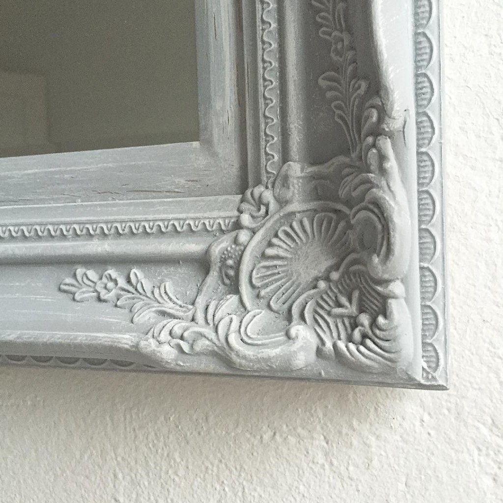 corner of large grey ornate mirror with slight white distressing