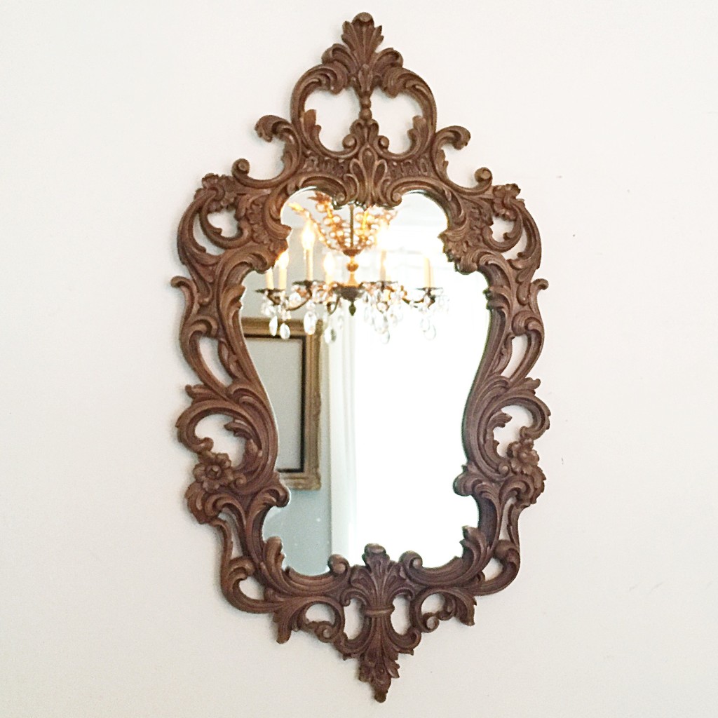 Ornate wood framed mirror with a crystal chandelier in the reflection. Ornate Mirrors Bring So Much Excitement to Home Decor