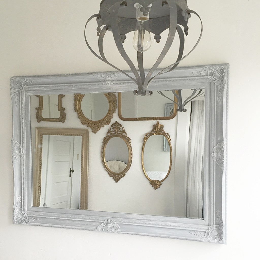 crown grey hanging light and large grey mirror with 6 gold mirrors in the reflection