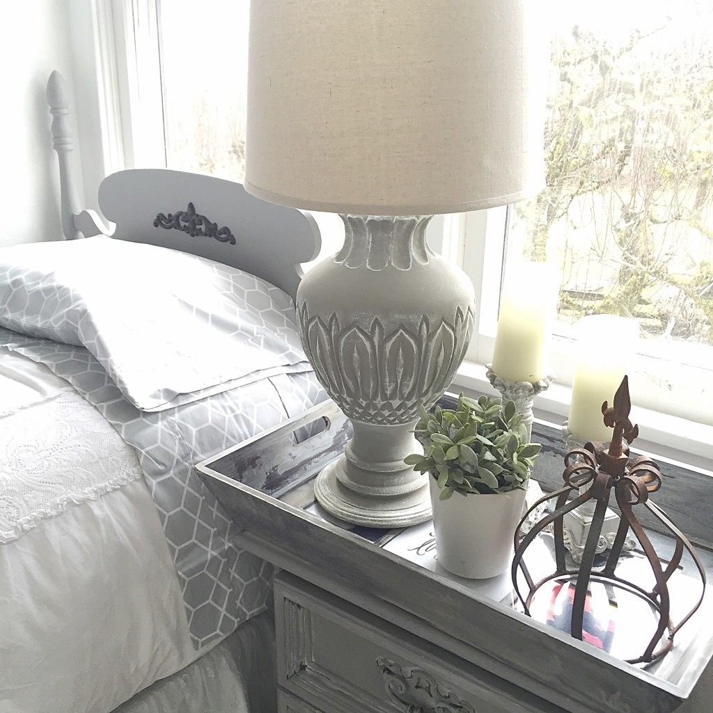 grey table lamp with white shade and rust french crown ontop of grey nightstand