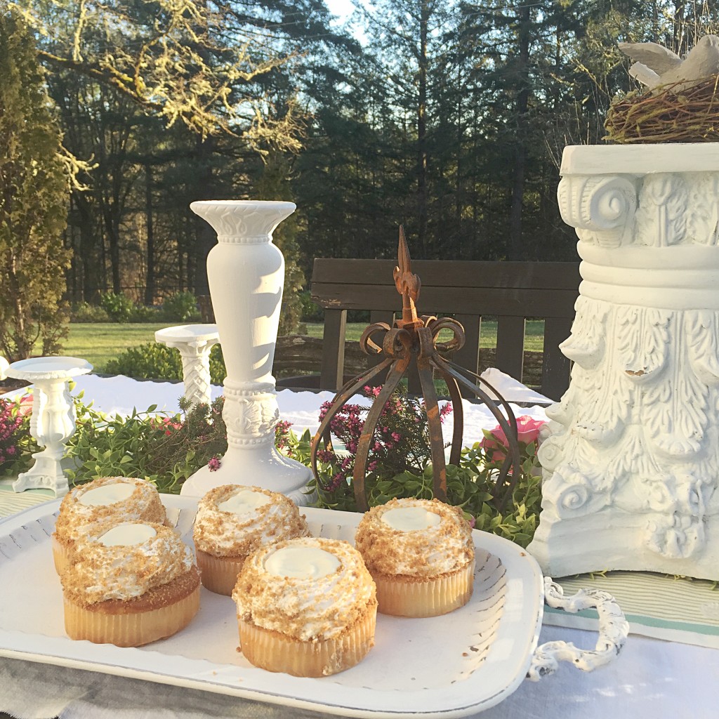 white cupcakes on white tray. rust crown and white candle hlders on table