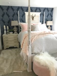 Canopy bed with pink throw blanket and pink pillows with a white fur rug