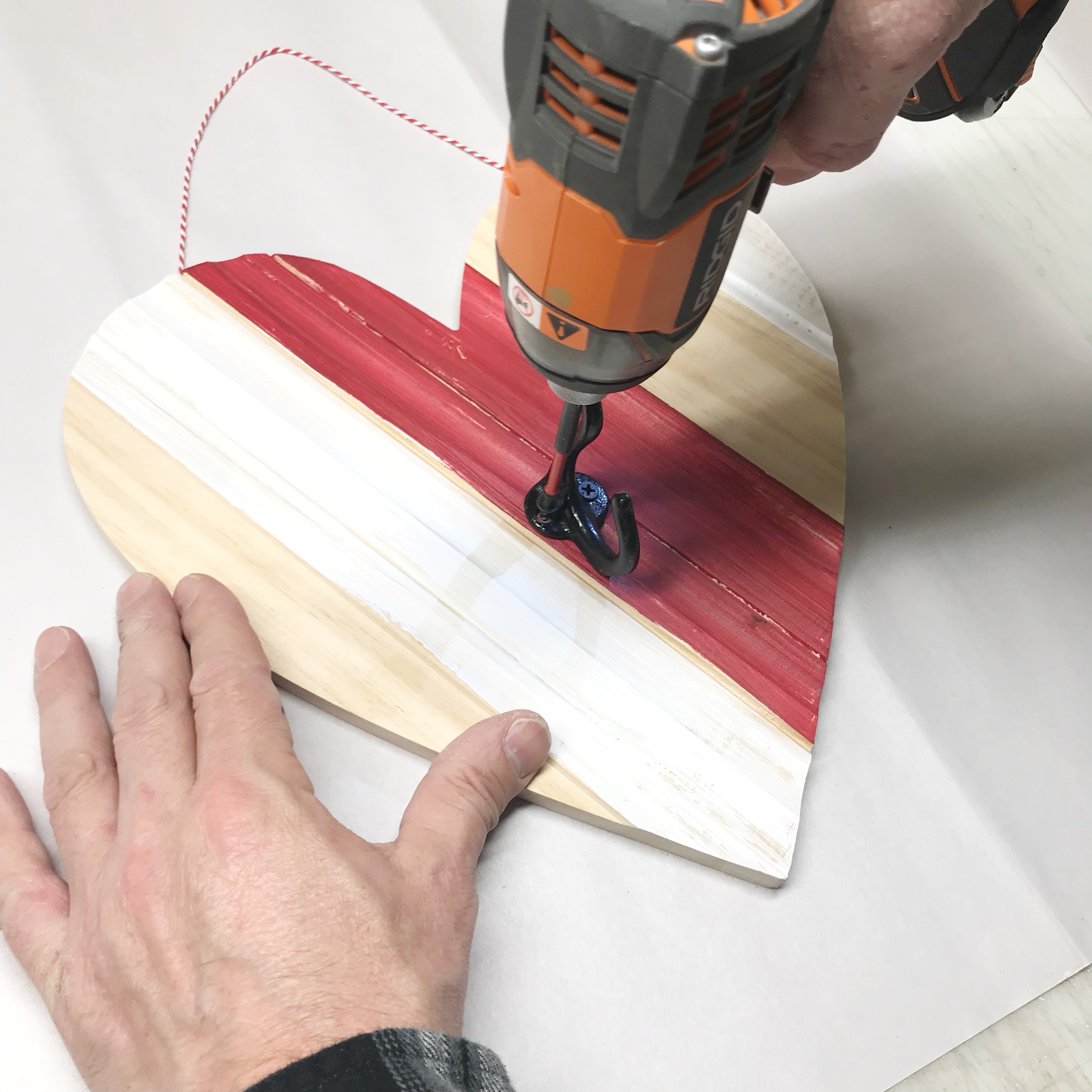 Drilling coat hook into striped heart shaped wall decor