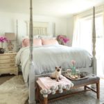 13 Tips for Making a Cozy Bedroom Retreat with bedroom view of white bedding with 2 pink linen pillows and 2 bouquets of pink orchids on each side of bed