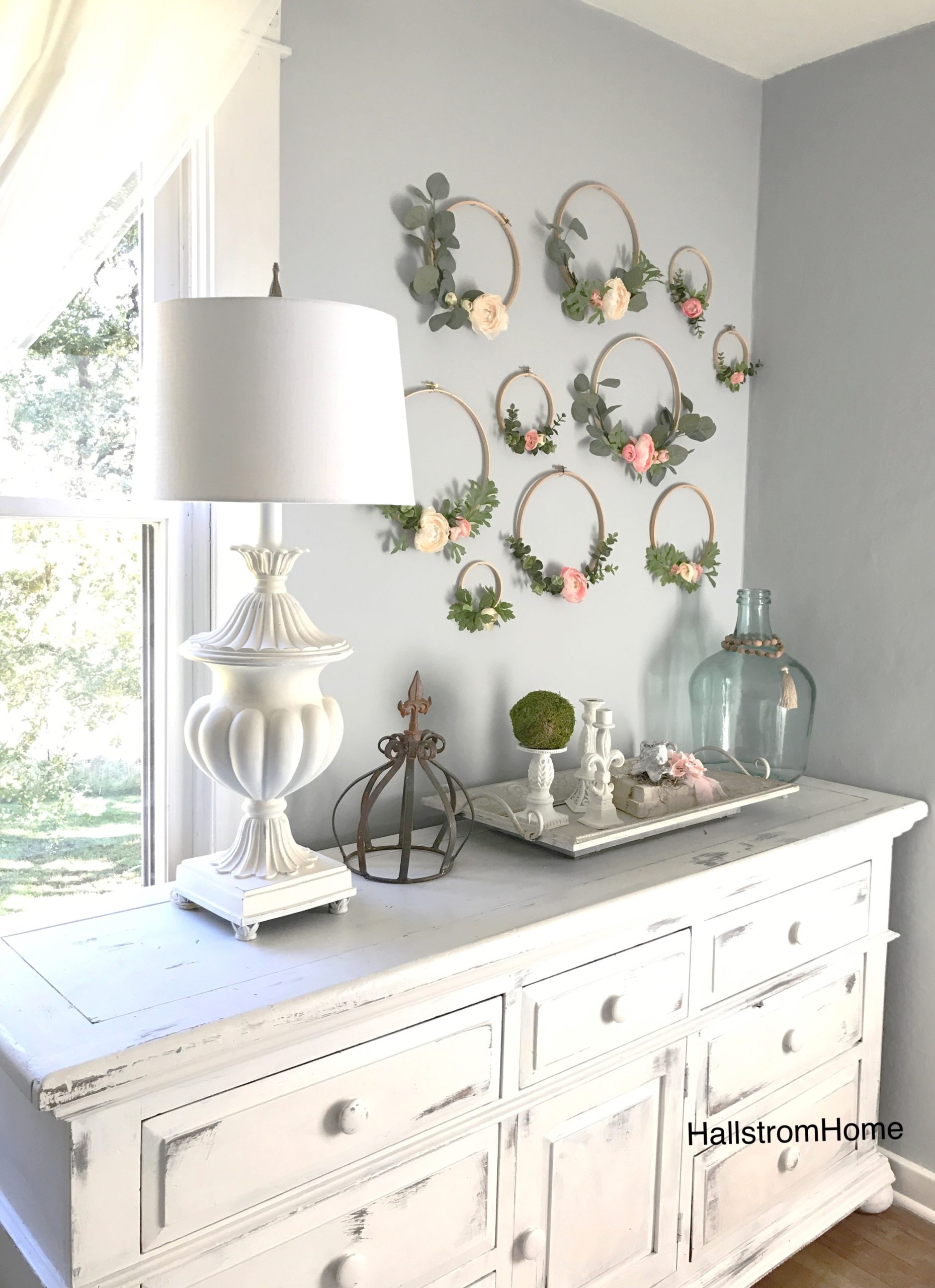 Making Hoop Wreaths for Spring with 10 embroidery hoops with flowers and greenery on wall above white dresser