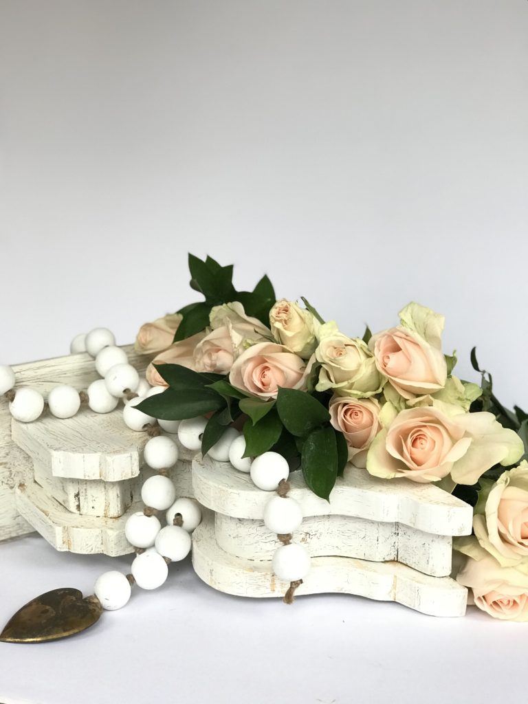How to Make White Wood Bead Garland a white chippy corbel with white wood bead garland draped ontop. bead garland has metal heart at the end and pink roses set ontop of corbel