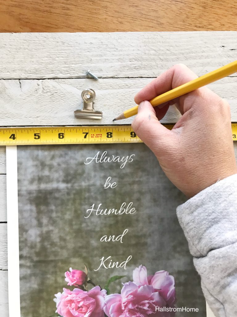 white wood board with yellow measuring tape and silver clamp