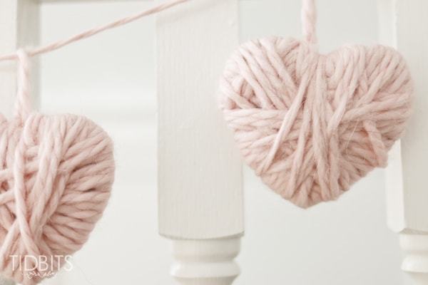 two light pink yarn hearts on a banner against white stair posts