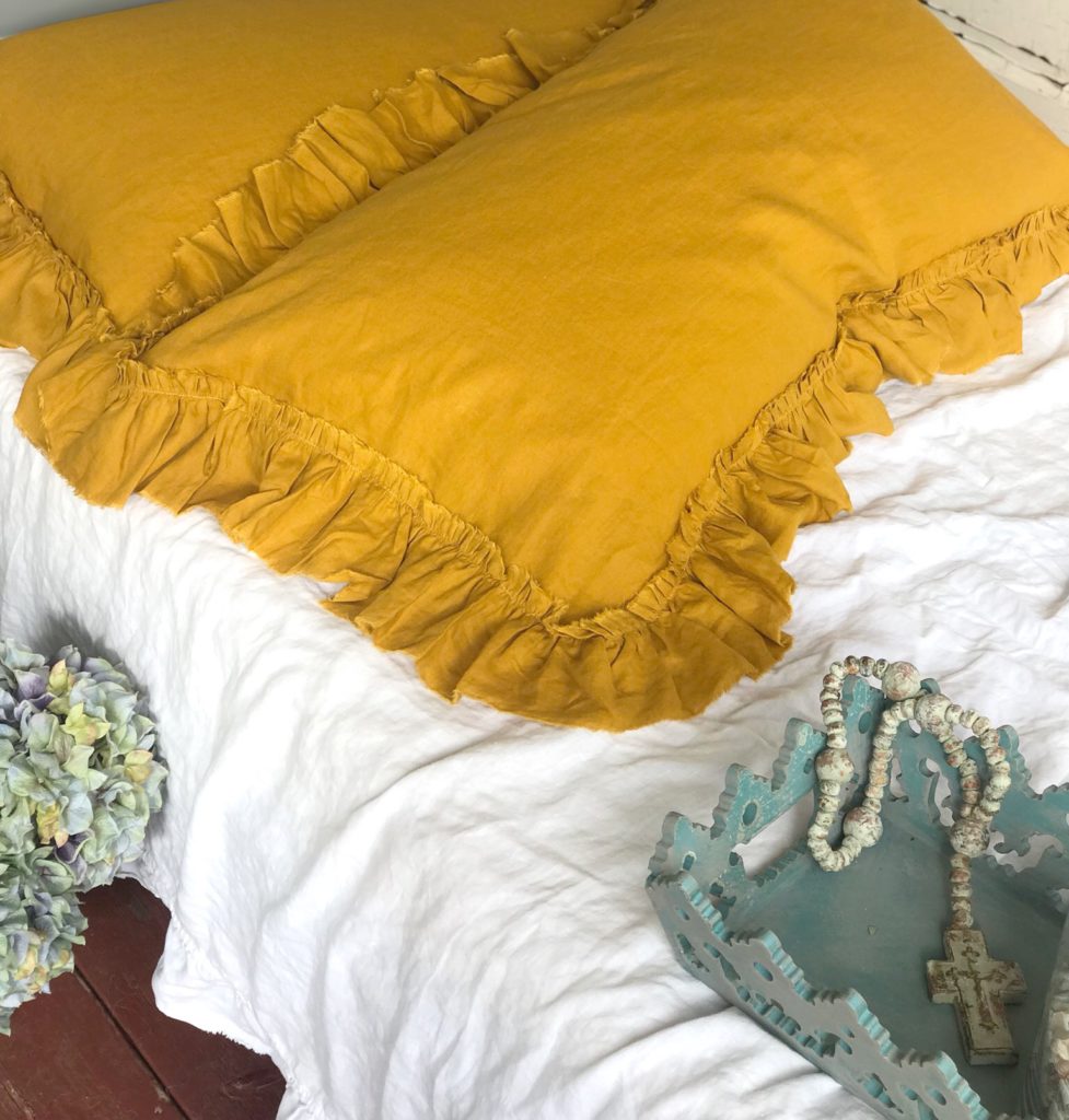 yellow linen shams on white bed spread with blue tray