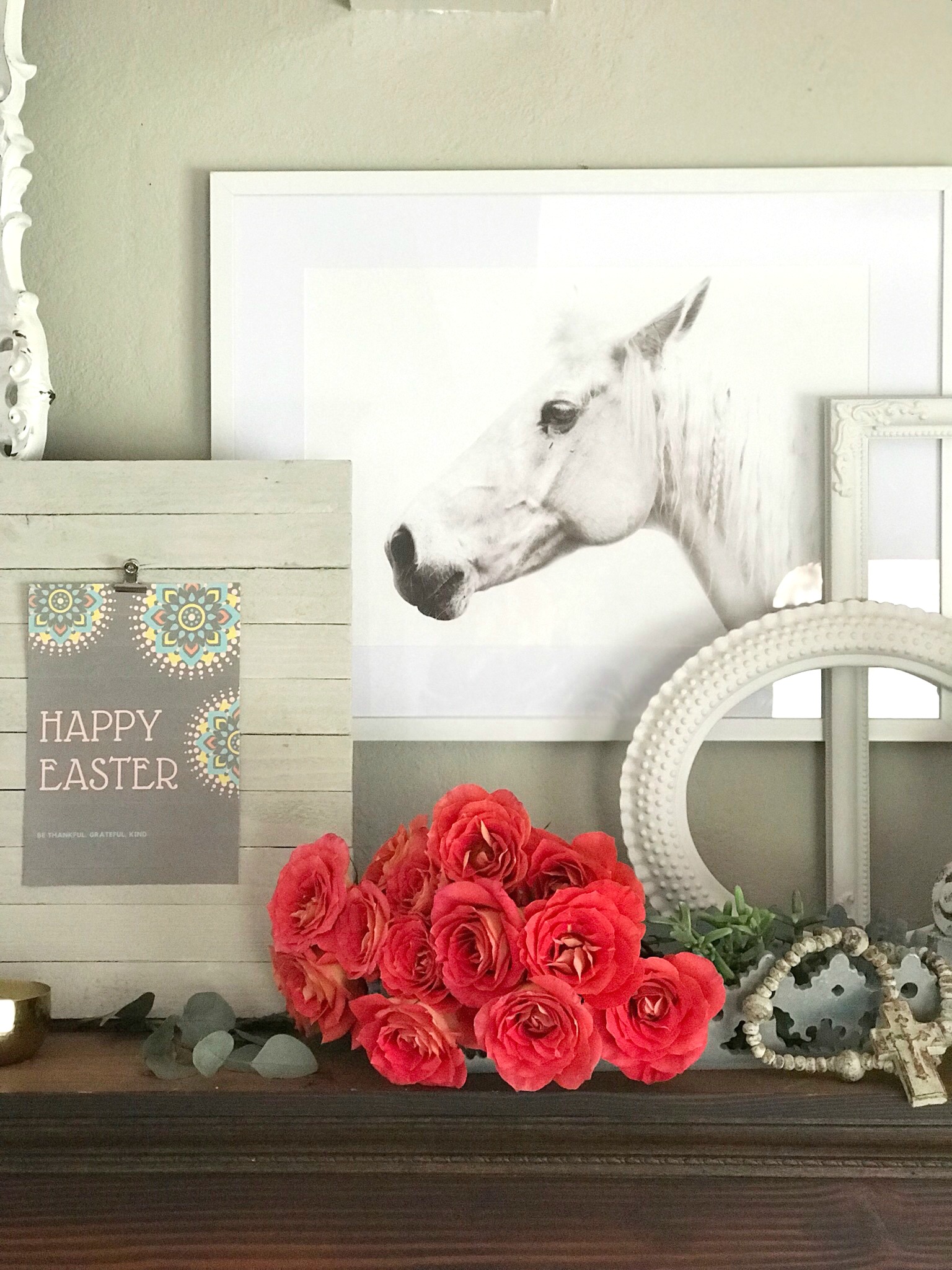 red bouquet of roses in a blue tray with cross bead garland in front of a happy easter printable with whit horse icture hanging