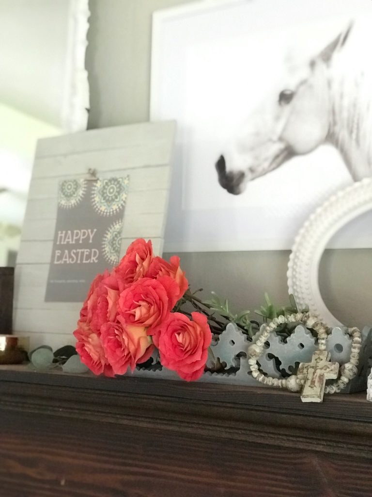 red bouquet of roses in a blue tray with cross bead garland in front of a happy easter printable with whit horse icture hanging
