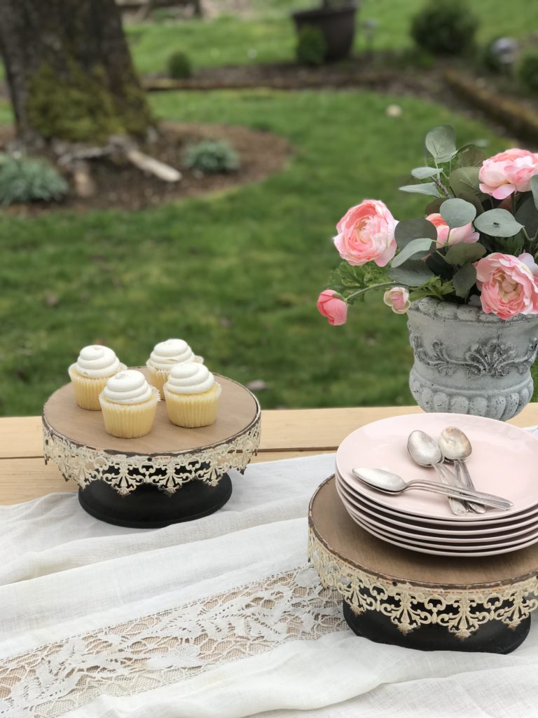 2 cake stands one with 4 white cupckaes and one with stack of pink plates