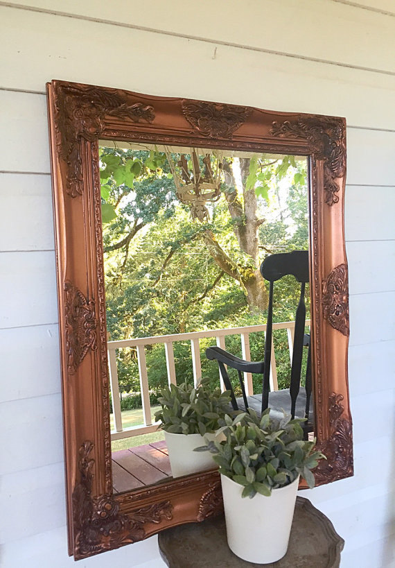 copper mirror against white wall reflection of rocking chair