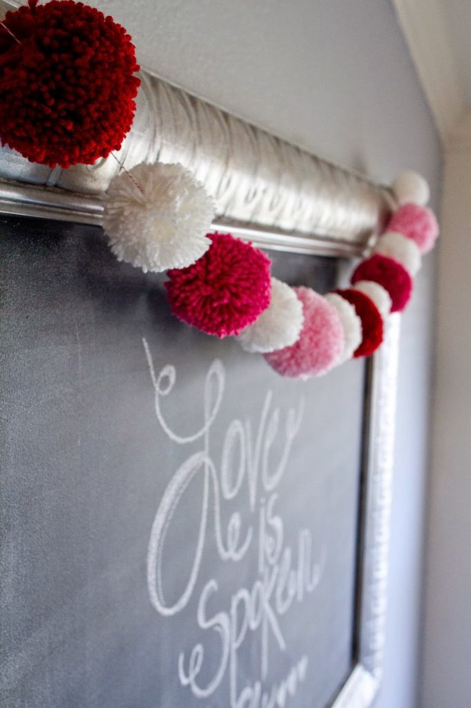 red white and pink pom pom garland draped over silver chalkboard