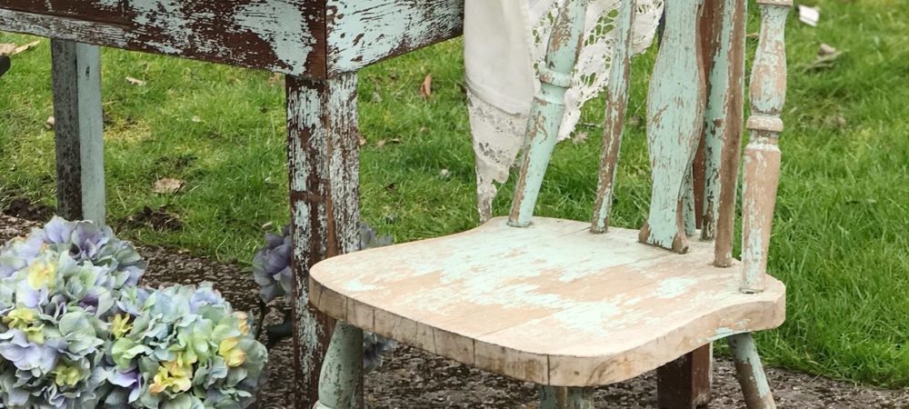 Our Farmhouse Decor from HallstromHome blue chippy chair next to antique blue chippy wood table with pot on ground with hyrdrangea bouquet