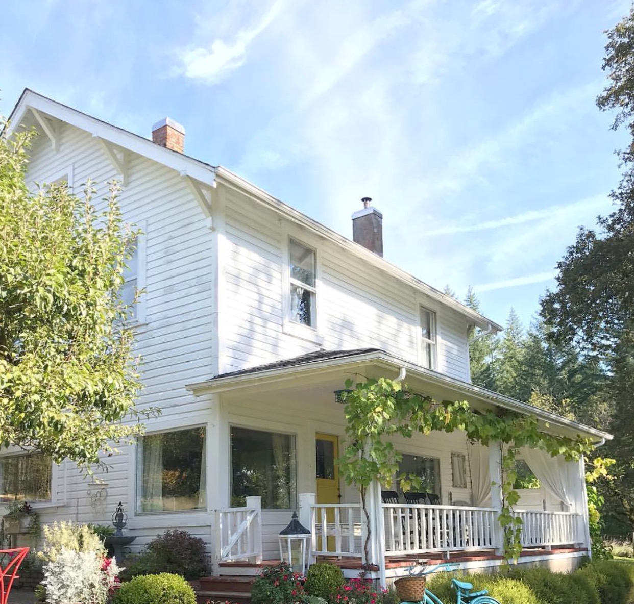 Our 100 Year Old Farmhouse Spring Tour white farmhouse with grapevines growing on porch and blue bicycle out front