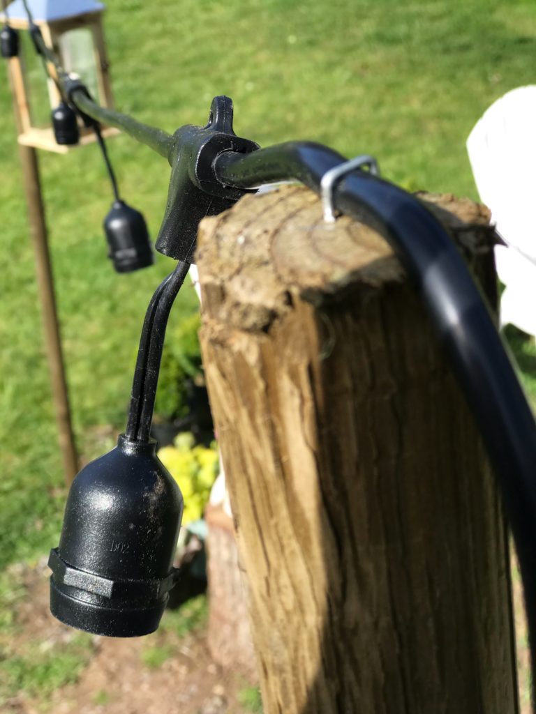 wood post with black wire light stapled in