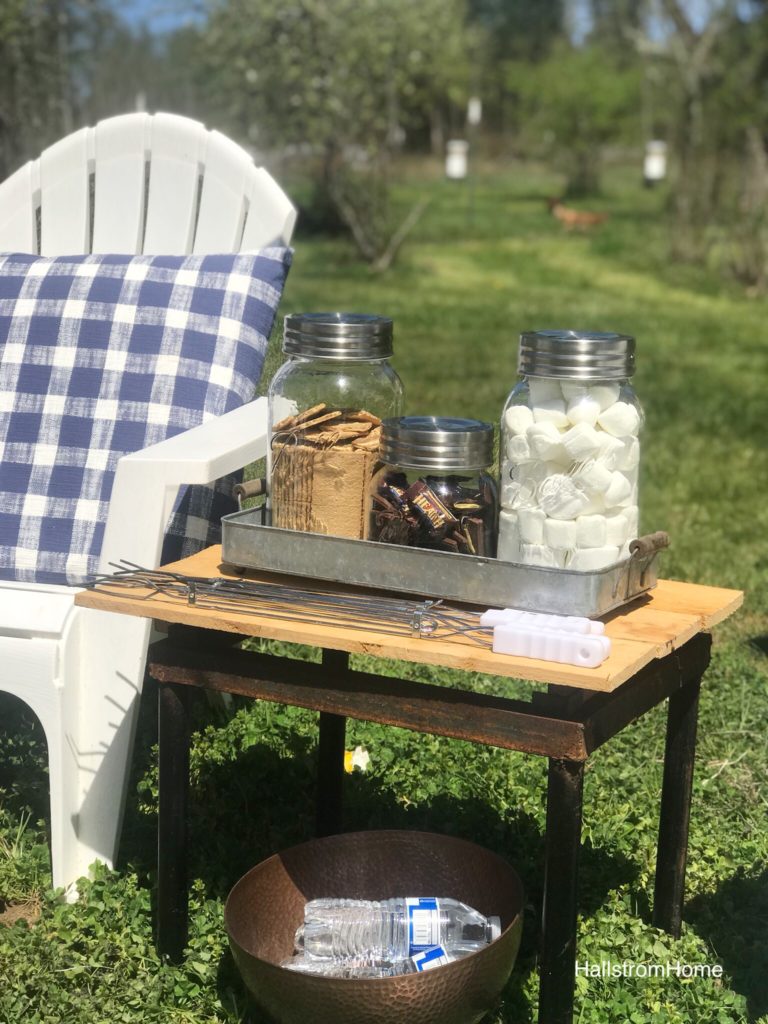 wood side table top with 3 jars filled with marshmallws, chocolate, and grahamcrackers