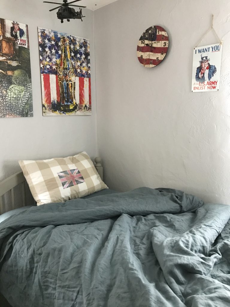 blue bedding with 2 puxxles hanging on wall with american flag clock