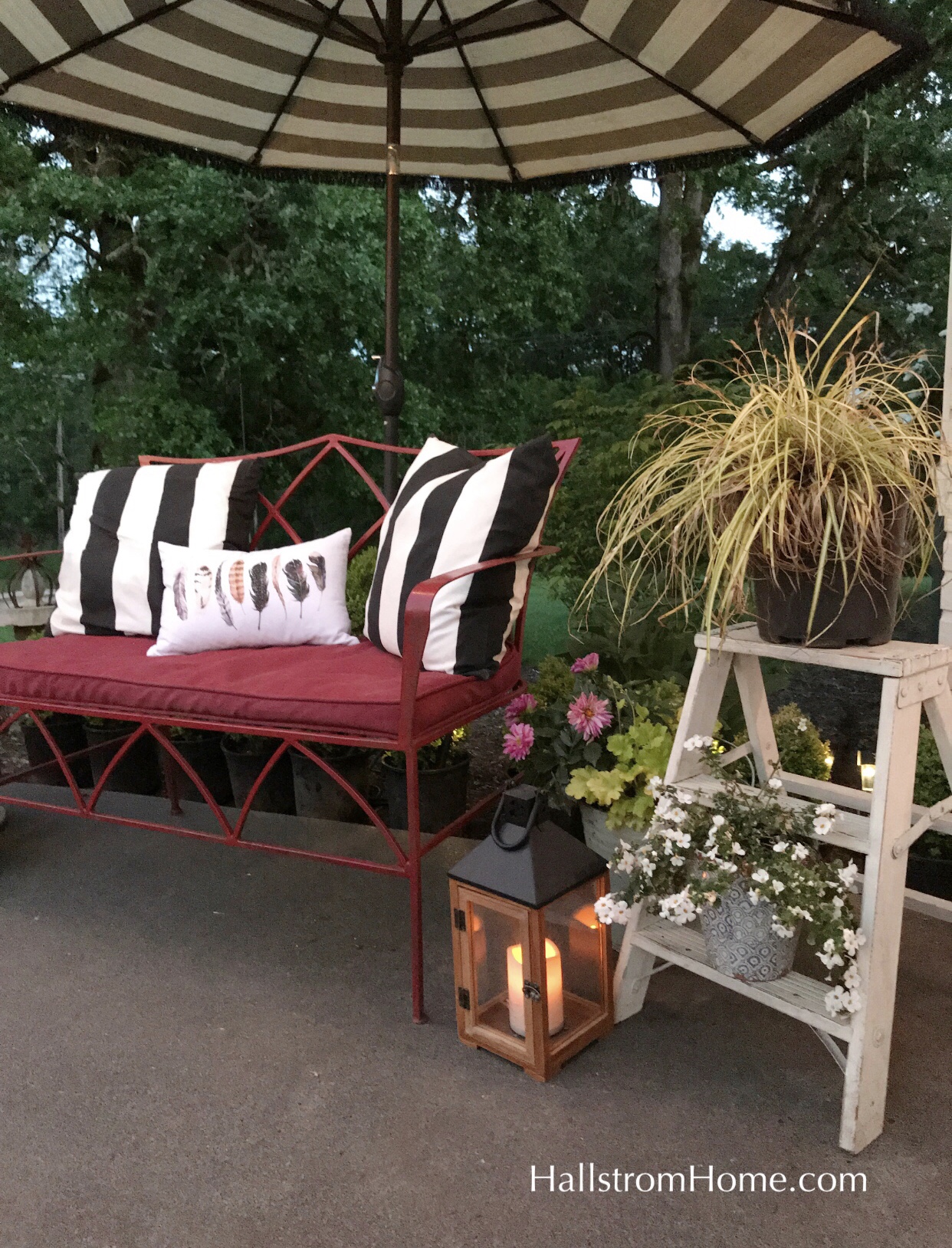 red bench with black and white stripe pillows and outdoor lantern on ground