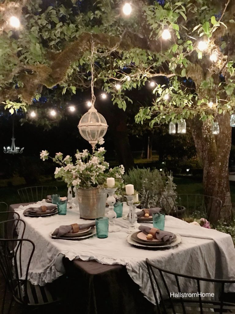 ruffle linen table cloth with 6 white candle holders and blue cups silver bucket with white flowers and round glass chandeleier