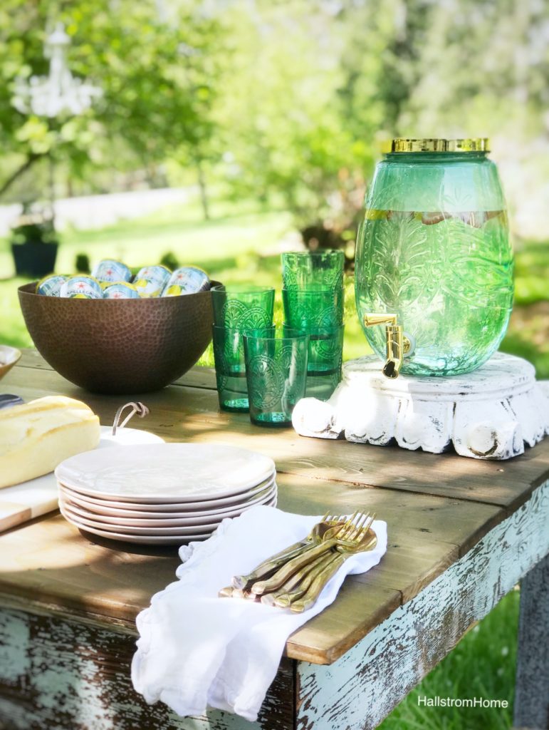 woodend table with blue pitcher stack of pink plates white linen napkins with gold silverware