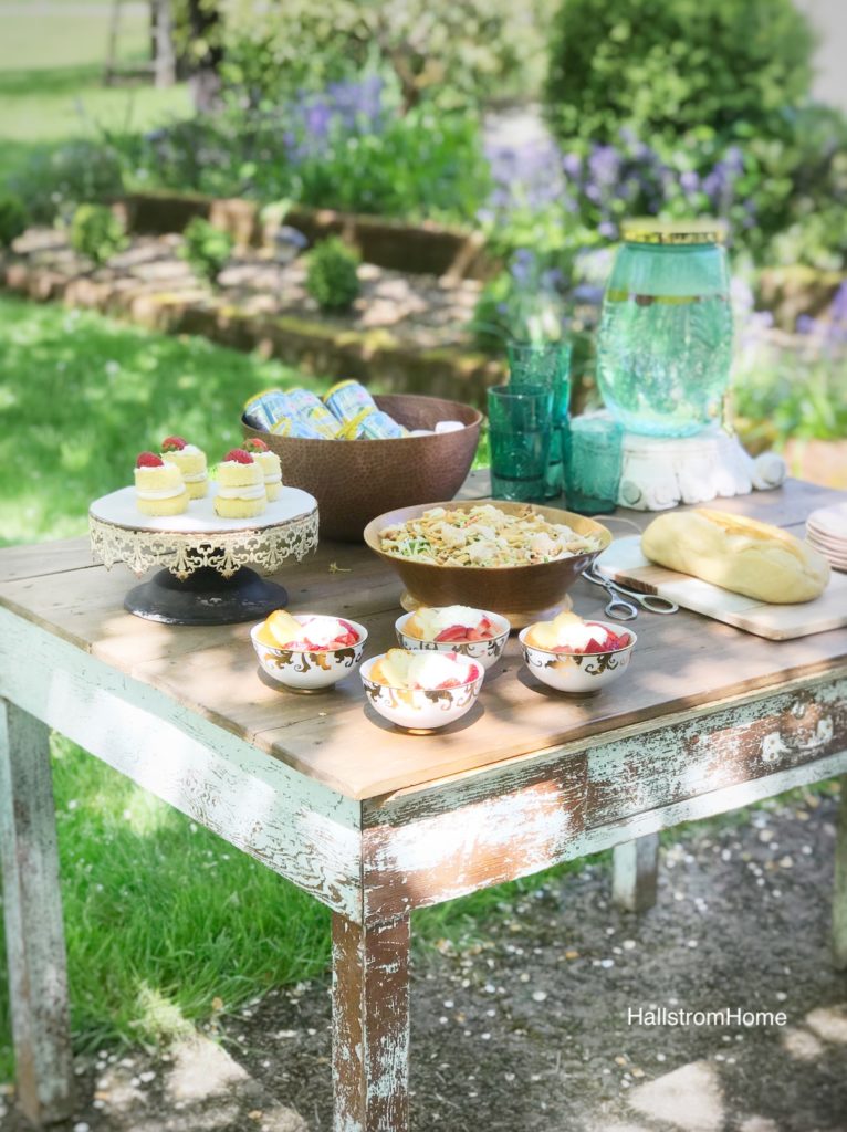 table with 4 bowls of strawberry shortcake platter of 4 cupcakes bowl of asian salad bread jug of water