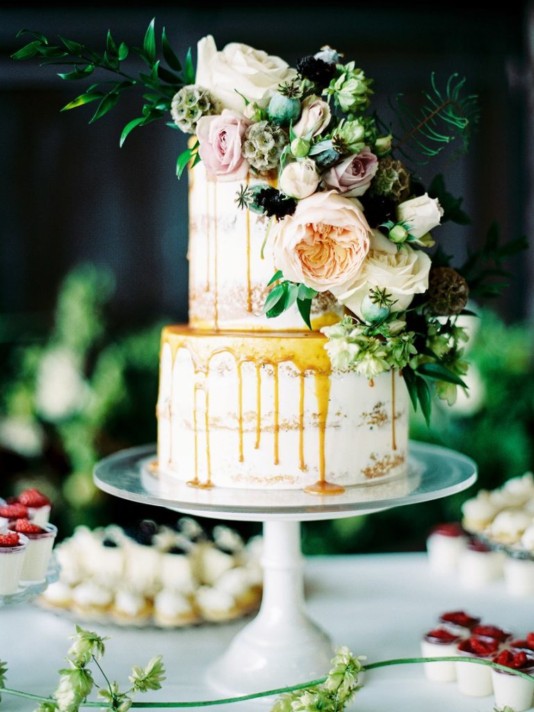 2 tier naked cake with dripping caramel and rases and greenery 