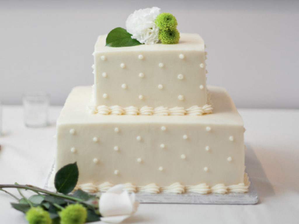 2 tier square cake with white frosring and polka dots on it