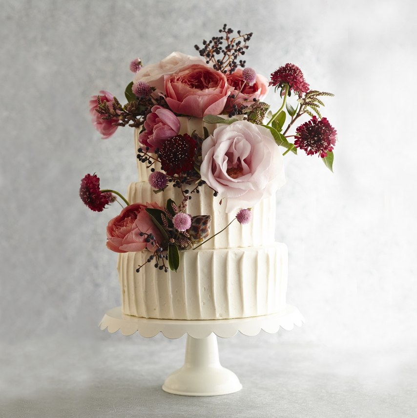 3 tier white frosted cake with pink flowers on it