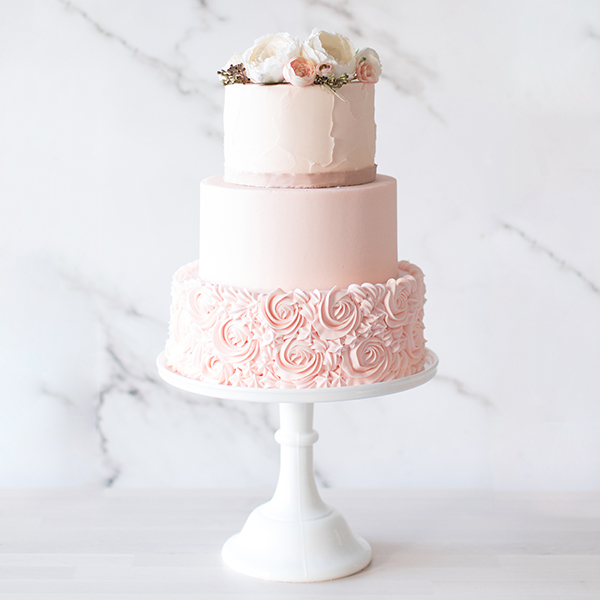 3 tier blush pink cake with white peonies on tip