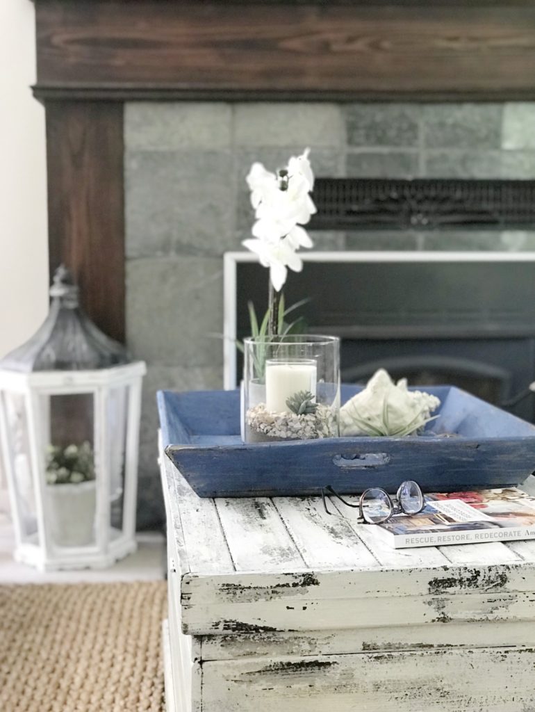 How To Make Relaxed Easy Farmhouse Style Home with Kids. Blue Chalk Painted Farmhouse Tray on white chippy painted trunk with clear candle and book with glasses
