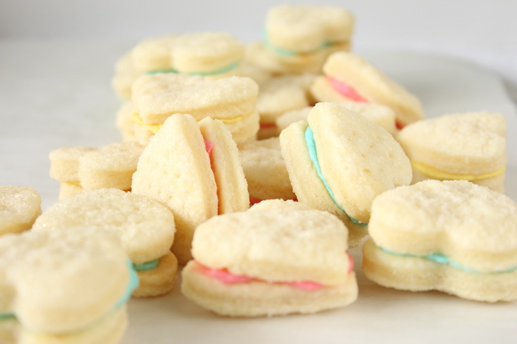 Many heart shaped wafer cookies filled with pink blue and yellow cream