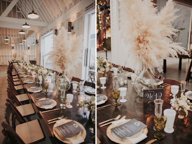 long table with gold charger and big glass vases with beach grass in them