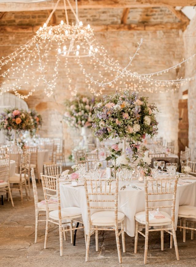 round table with white chippy chairs and tall centerpiece with purple and pink flowers 