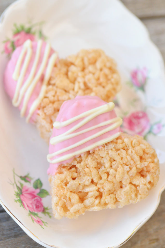 2 heart shaped rice krispies with corner dipped in pink with lines of white