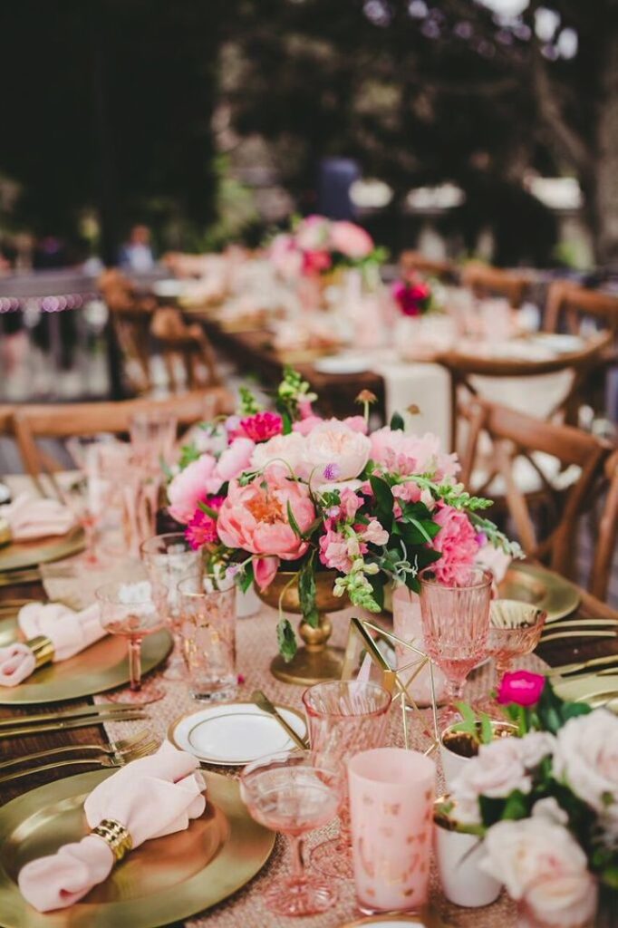 pink cups and pink flowers and gold chargers on wedding table