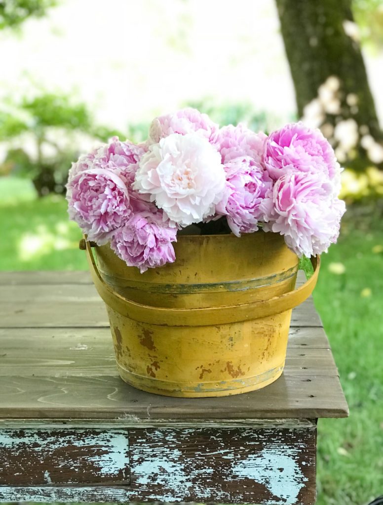 Yellow chippy wood bucket with pink flowers in it