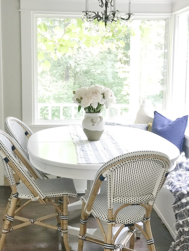 How to Get a Simple Yet Beautiful Farmhouse Style/Home Tour white dining table with 3 blue and white chairs and bench with vase and bouquet of pink flowers