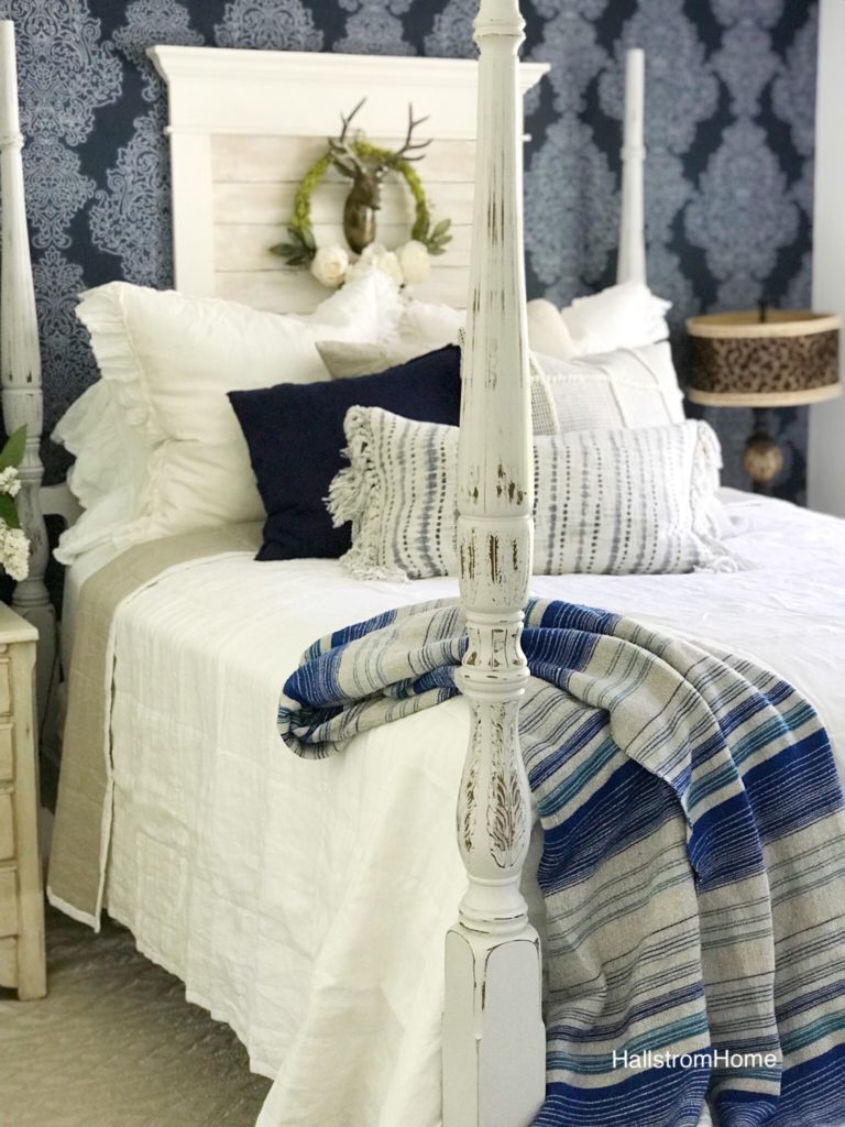 white bedding with blue blanket and 2 blue pillows