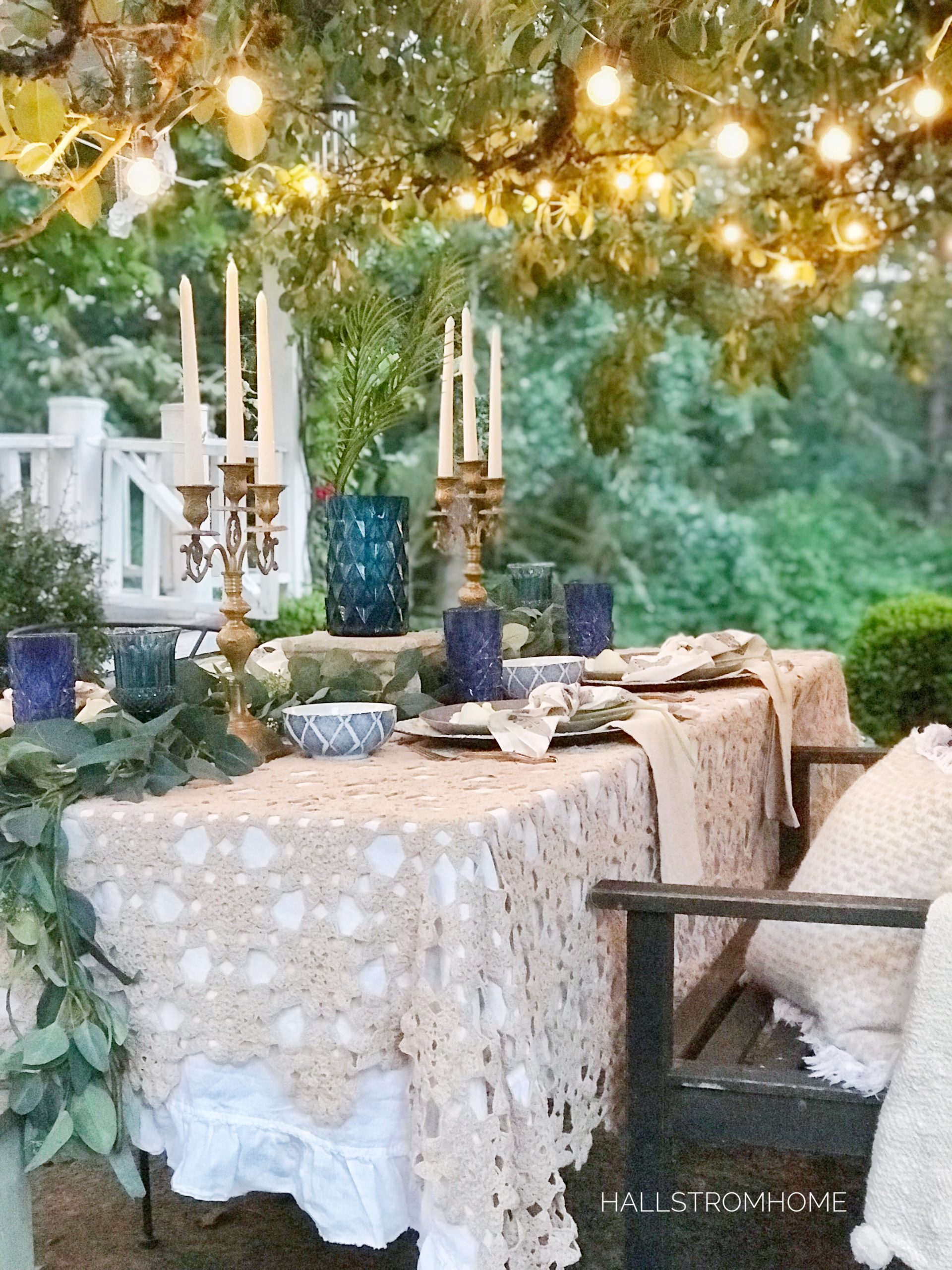 How to Get a Simple Yet Beautiful Farmhouse Style/Home Tour lace table cloth outside with blue cups and vase with gold candelabras and lights above on tree