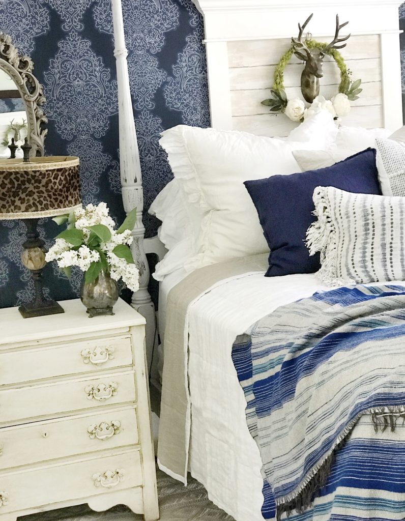 white bedding with blue blanket and 2 blue pillows