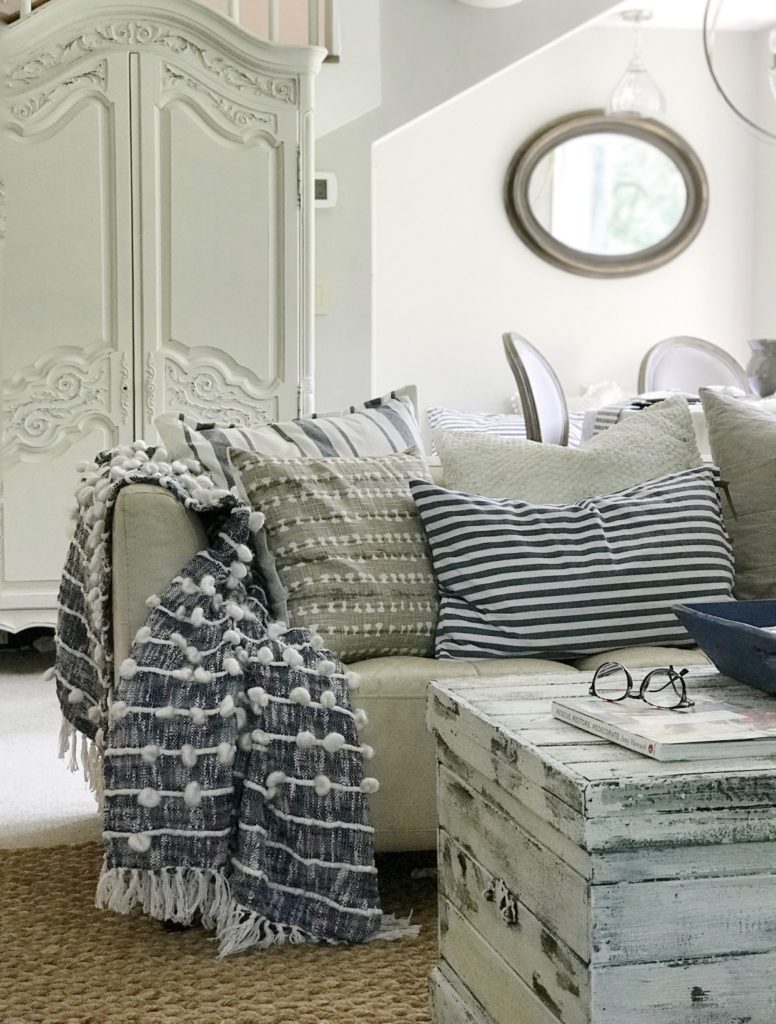 white chippy trunk with couch and blue blanket with 5 blue and white and natural pillows