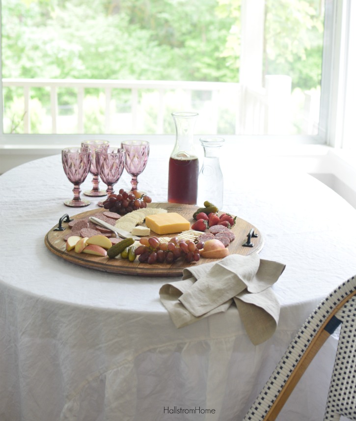 cheese platter on white table with 4 cups and pitcher of iced tea