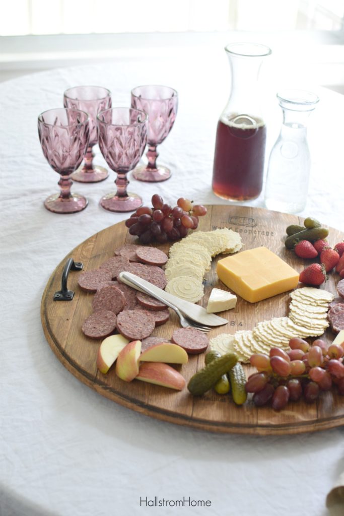 How to Make a Wine Barrel Cheese Board the Easy Way with cheese crackers pickles apples and four glasses