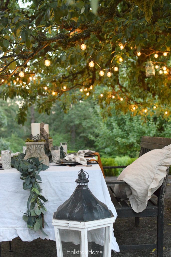 fall table with roostr centerpiece and greenery down middle with bench full of linen shams