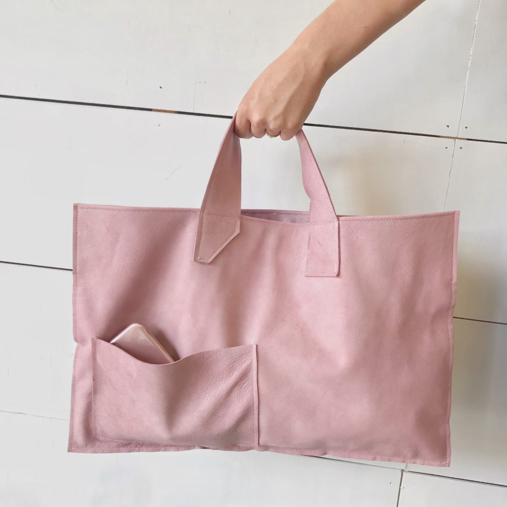 We Have a Fabulous Surprise-Launching a New Product, What Do You Think? hand holding pink leather bag with phone in front pocket