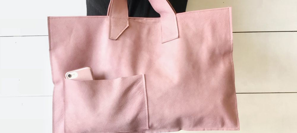 girl in black holding large pink leather bag