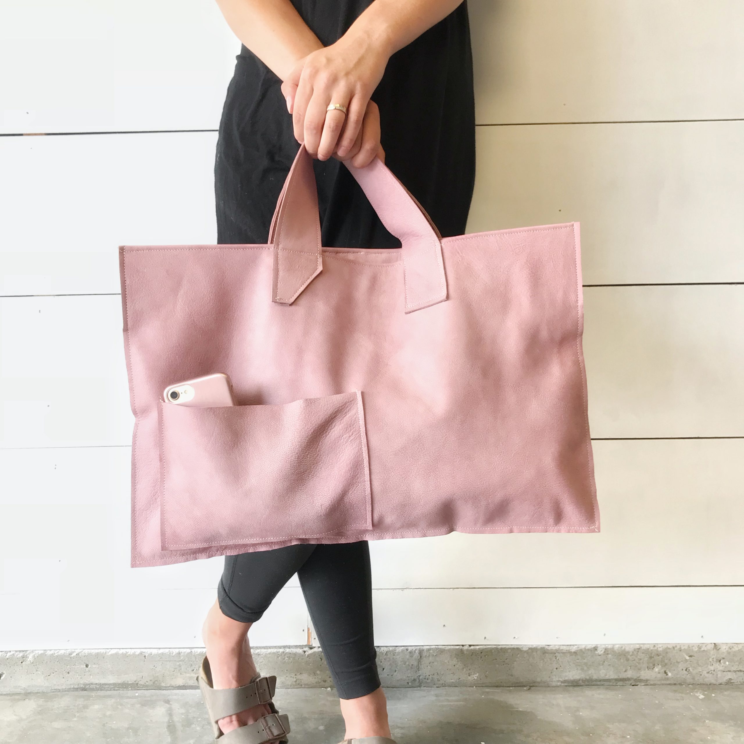 girl in black holding large pink leather bag