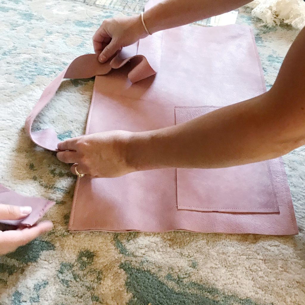 pink leather bag on ground with straps being held up